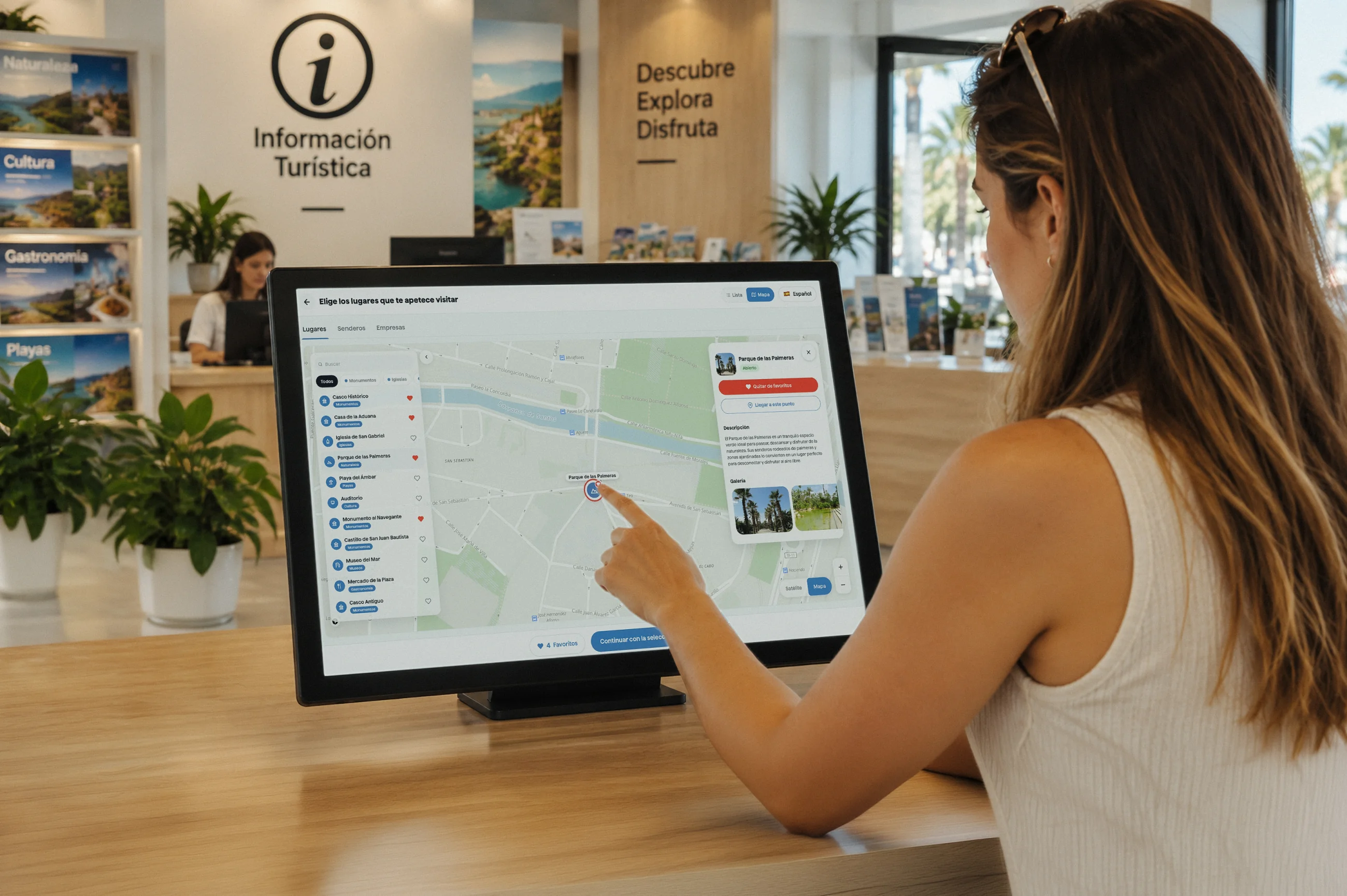 Una trabajadora de la oficina de turismo prepara con el visitante un itinerario en la pantalla del mostrador